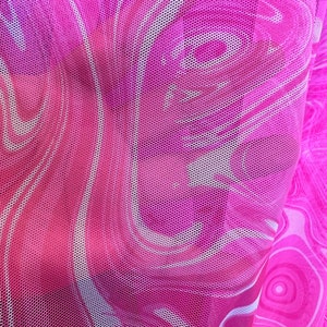K&ouml;nnte beinhalten: Nahaufnahme eines transparenten rosa Mesh-Stoffs mit einem wirbelnden, marmorierten Muster in Rosa- und Wei&szlig;t&ouml;nen. Der Stoff hat eine feine, wabenartige Textur, die einen halbtransparenten Effekt erzeugt. Das Design erinnert an Fluidit&auml;t und Bewegung.