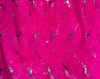 May include: Bright pink fabric with a diagonal pattern of silver and iridescent sequins and small dots. The sequins and dots are scattered across the fabric, creating a sparkling effect. The fabric is slightly wrinkled.