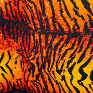 Puede incluir: Primer plano de una tela con un patr&oacute;n de rayas de tigre en naranja, amarillo y negro.