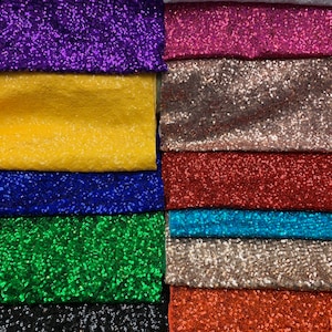 Puede incluir: Una colección de diez muestras de tela con diferentes colores de lentejuelas. Los colores incluyen morado, amarillo, dorado, rojo, azul, verde, negro y naranja.