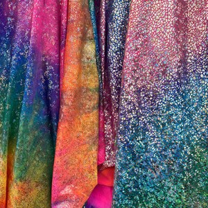K&ouml;nnte beinhalten: Vier verschiedene irisierende Stoffe mit einem Regenbogenfarbverlauf. Die Stoffe haben eine strukturierte, glitzernde Oberfl&auml;che.