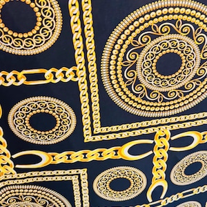 May include: A dark navy fabric featuring a repeating pattern of gold chain links, circles, and square frames. The design has intricate details and a luxurious aesthetic, suitable for fashion or home decor.
