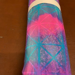 May include: A roll of iridescent pink and blue fabric with a geometric pattern. The fabric has a mesh texture and is rolled up with a white band.