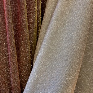 Peut inclure: Deux morceaux de tissu scintillant, l'un est rouge foncé avec des paillettes dorées et l'autre est argenté clair avec des paillettes argentées.