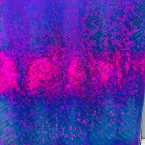 Op de afbeelding: Een close-up van een iriserende stof met een blauw en roze ombre-patroon. De stof heeft een textuur en een glinsterende afwerking.