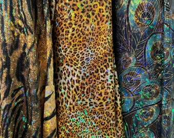 May include: Three different iridescent fabrics with animal print designs. The fabric on the left has a black and gold zebra print, the middle fabric has a brown and gold leopard print, and the fabric on the right has a blue and gold peacock feather print.