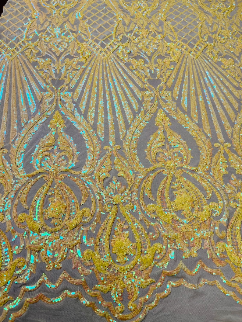 May include: A close-up of iridescent yellow fabric with a damask pattern. The fabric is made of sequins and has a subtle sheen.