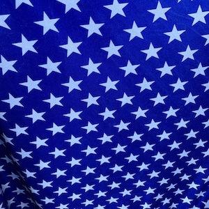 May include: A blue fabric with a repeating pattern of white stars. The stars are arranged in a diagonal pattern.