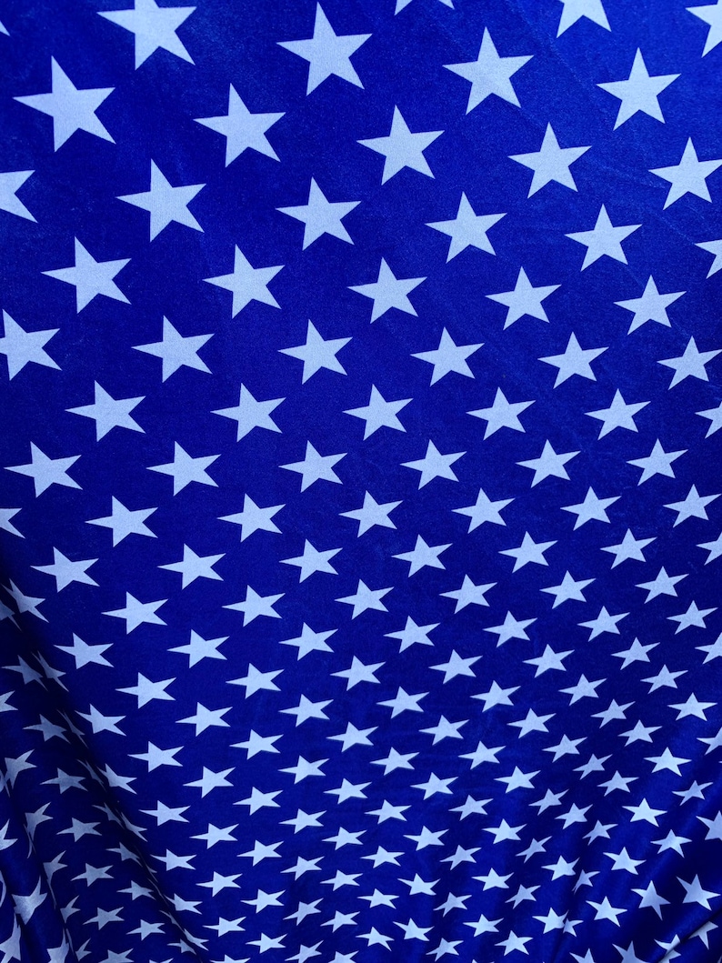 May include: A blue fabric with a repeating pattern of white stars. The stars are arranged in a diagonal pattern.