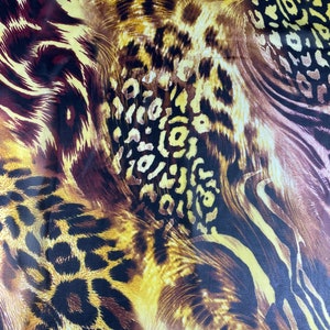 May include: Abstract fabric with a brown, yellow, and black leopard print pattern.