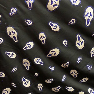 May include: Black fabric with a repeating pattern of white ghost face masks with blue glitter accents.