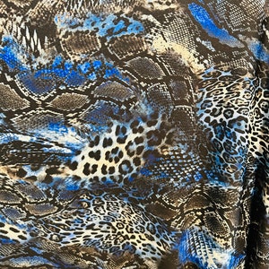 Puede incluir: Tela azul y negra con un patrón de estampado de serpiente y leopardo.