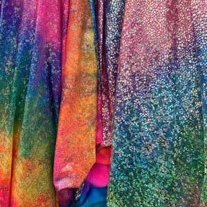 K&ouml;nnte beinhalten: Vier St&uuml;cke regenbogenfarbener, schimmernder Stoff. Der Stoff hat eine strukturierte, glitzernde Oberfl&auml;che.