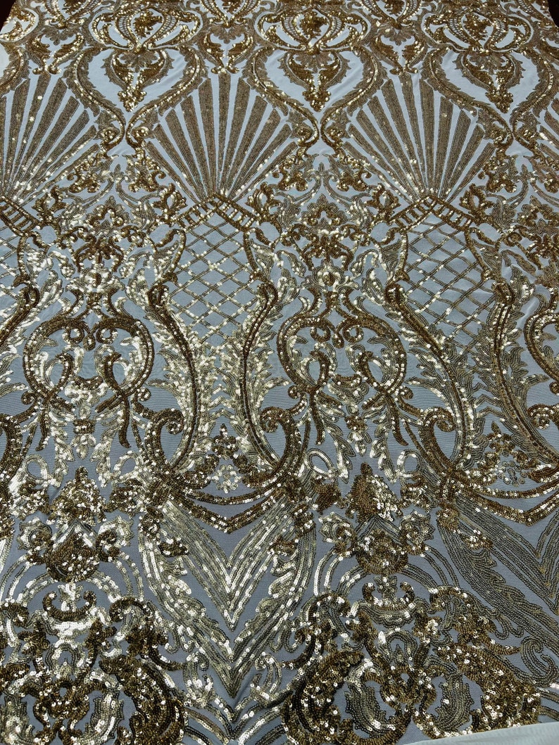 May include: Gold sequin fabric with a white background and a damask pattern.
