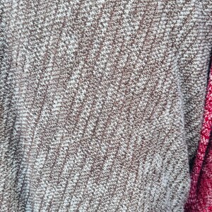 K&ouml;nnte beinhalten: Nahaufnahme eines braunen und wei&szlig;en Strickstoffes mit diagonalem Muster. Der Stoff ist weich und texturiert, mit einem dezenten Glanz.
