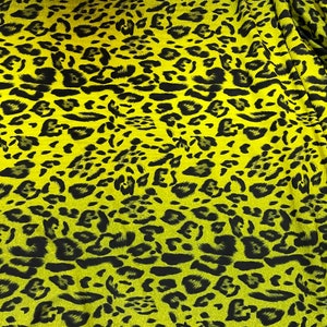 Puede incluir: Una tela amarilla con un estampado de leopardo negro. La tela tiene un efecto degradado, con el amarillo más claro en la parte superior y más oscuro en la parte inferior.