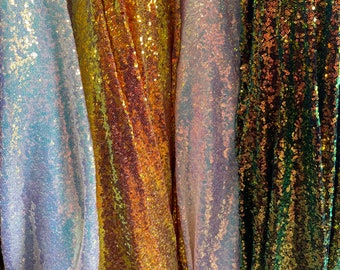 Puede incluir: Cuatro muestras de tela iridiscente diferentes con una textura de lentejuelas. Las muestras son en tonos de blanco, dorado, rosa y verde.