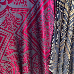 May include: Two pieces of fabric with a damask pattern. One fabric is a dark red velvet with a black background. The other fabric is a black velvet with a gold background.