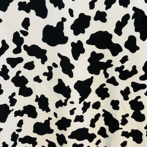 May include: Black and white cow print fabric with a gradient pattern. The fabric has a smooth texture and is perfect for crafting projects.