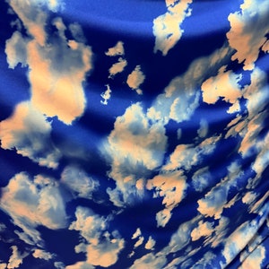 May include: Blue fabric with a white cloud print. The fabric has a satin-like sheen.