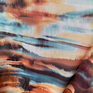 May include: Abstract fabric with a blue, brown and orange watercolour-style design. The fabric has a flowing, wavy pattern.