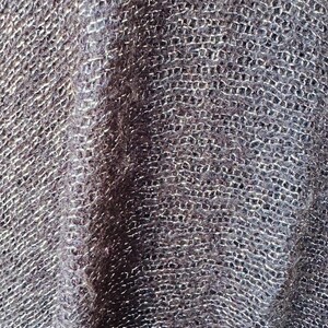 Puede incluir: Primer plano de una tela de punto gris oscuro con un brillo sutil. La tela tiene un patr&oacute;n tejido texturizado.