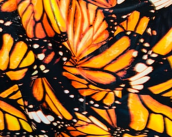 May include: A close-up of a fabric with a repeating pattern of orange and black monarch butterfly wings.