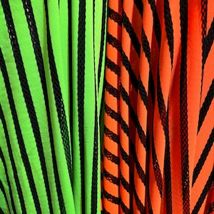 May include: Two fabric swatches with black stripes on a green and orange background. The fabric has a mesh texture.