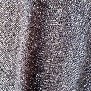 Puede incluir: Primer plano de una tela de punto gris oscuro con un brillo sutil. La tela tiene un patr&oacute;n tejido texturizado.