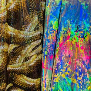 以下が含まれることがあります： 2つの生地サンプル。1つは金と茶色のヘビ柄です。もう1つは、青、ピンク、黄色、緑の色合いが混ざった鮮やかな虹色の生地です。これらの生地は、アパレルやクラフトプロジェクトに使用される可能性があります。