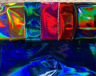 May include: A close-up of six iridescent fabric swatches in different colors: silver, gold, turquoise, fuchsia, red, and black. The swatches are arranged horizontally, with the silver swatch on the left and the black swatch on the right. The fabric is shiny and reflective, and the colors are vibrant and eye-catching.