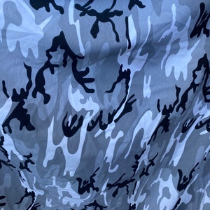 May include: A close-up of a grey and black camouflage fabric with a wrinkled texture.