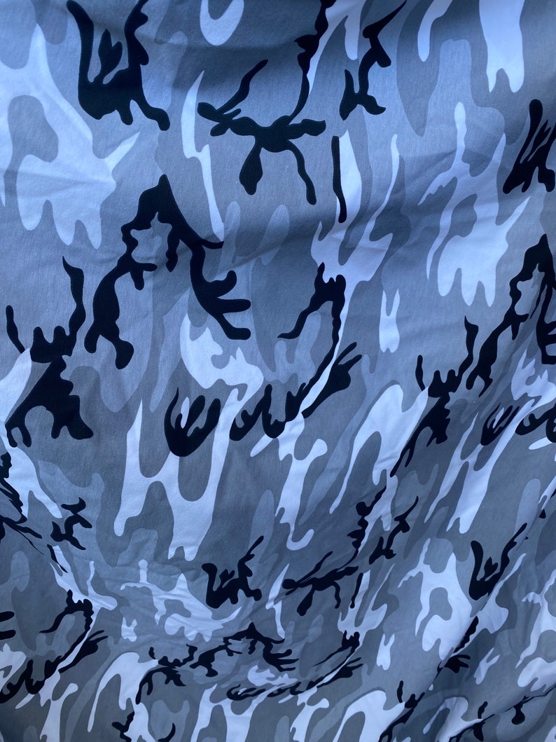 May include: A close-up of a grey and black camouflage fabric with a wrinkled texture.