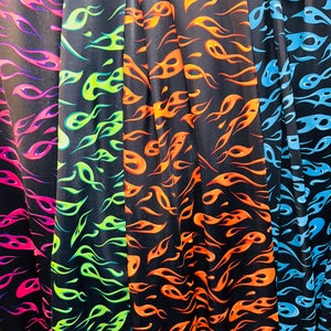Puede incluir: Cuatro muestras de tela con fondo negro y un patr&oacute;n de llamas en diferentes colores: rosa, verde, naranja y azul.
