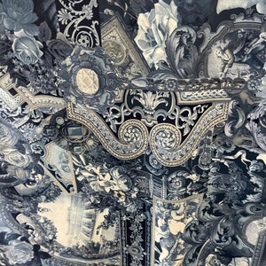 May include: A black and white fabric featuring a repeating pattern of ornate floral designs, scrolls, and architectural elements. The fabric has a vintage feel and would be ideal for upholstery or curtains.