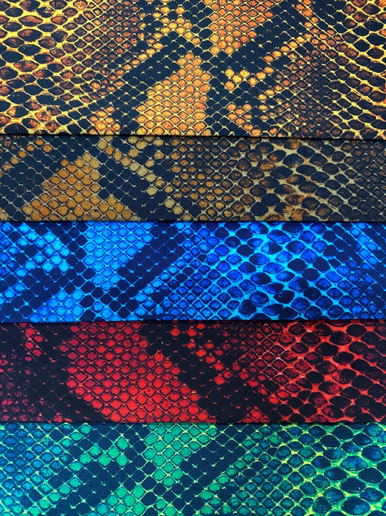 May include: Five different fabric swatches with a snake skin pattern. The swatches are in the colours brown, blue, red, green, and black.