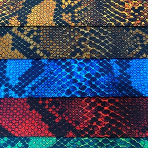 May include: Five fabric swatches featuring a snake skin pattern. The swatches are arranged vertically, with the top swatch being a brown and gold snake skin pattern, followed by a brown and black snake skin pattern, then a blue snake skin pattern, then a red and black snake skin pattern, and finally a green and black snake skin pattern.