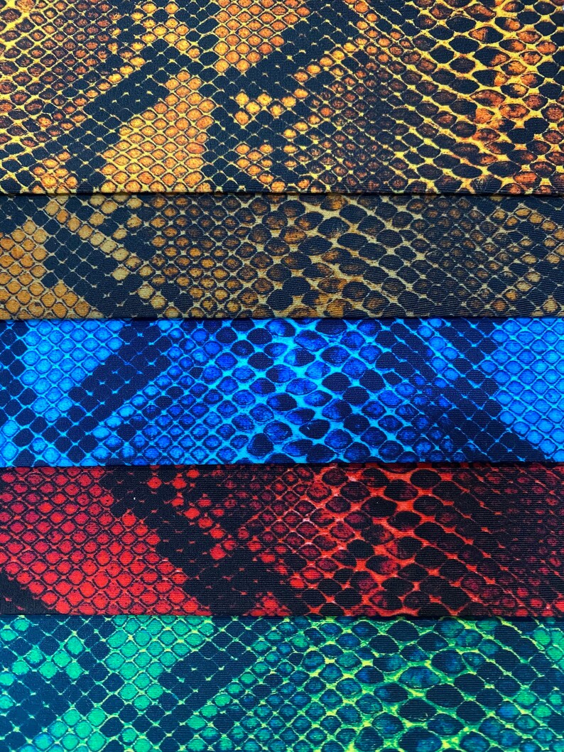 May include: Five fabric swatches featuring a snake skin pattern. The swatches are arranged vertically, with the top swatch being a brown and gold snake skin pattern, followed by a brown and black snake skin pattern, then a blue snake skin pattern, then a red and black snake skin pattern, and finally a green and black snake skin pattern.