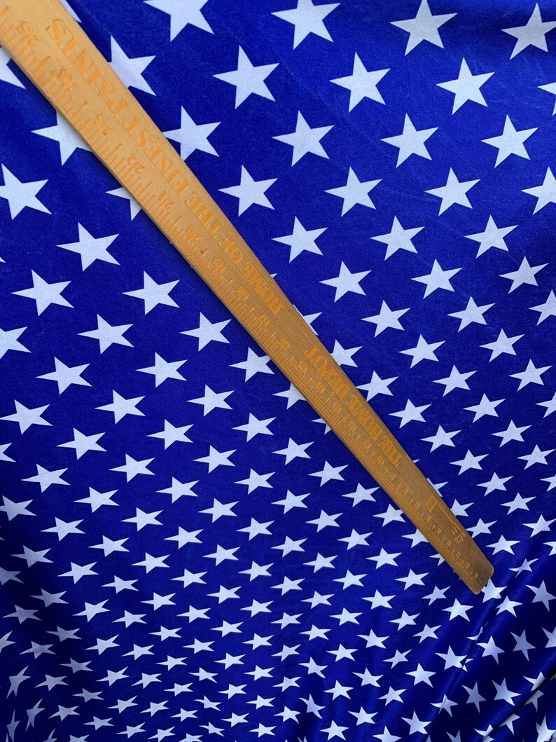 May include: Blue fabric with a white star pattern. The fabric is measured with a wooden ruler.