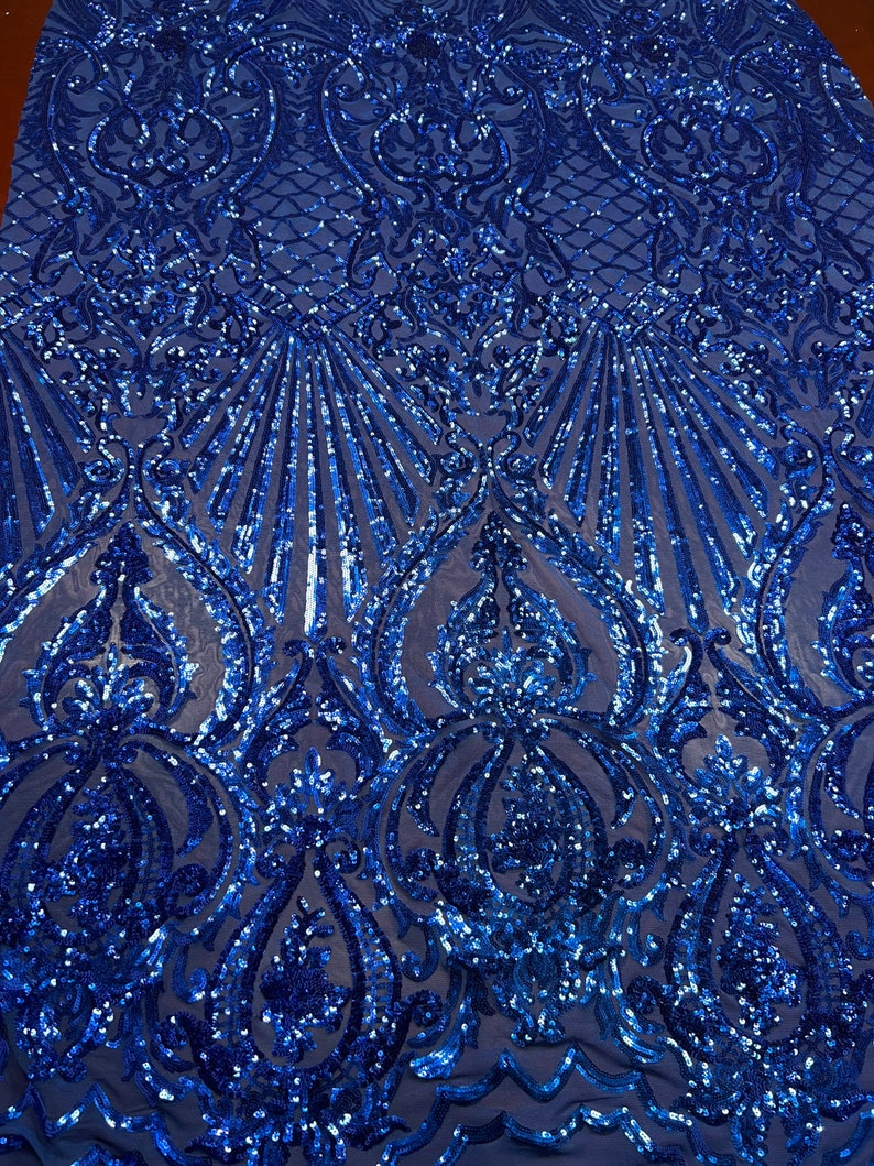 Puede incluir: Tela azul real con lentejuelas con un patr&oacute;n de damasco. Las lentejuelas est&aacute;n dispuestas en un patr&oacute;n repetitivo de espirales y hojas.