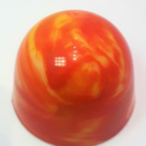 Puede incluir: Un caramelo redondo, naranja y amarillo con un patr&oacute;n de remolino marmoleado.