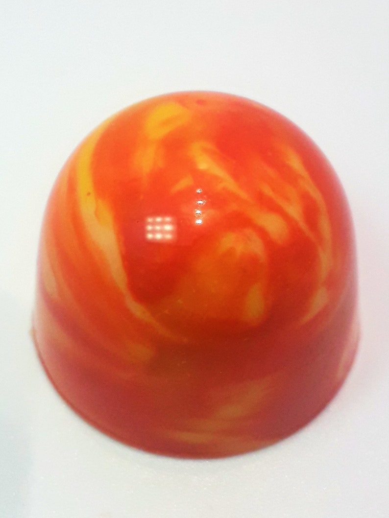 Puede incluir: Un caramelo redondo, naranja y amarillo con un patr&oacute;n de remolino marmoleado.