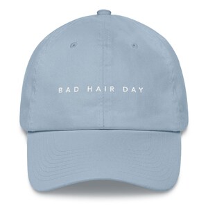 May include: A light blue baseball cap with the text "BAD HAIR DAY" embroidered in white on the front.