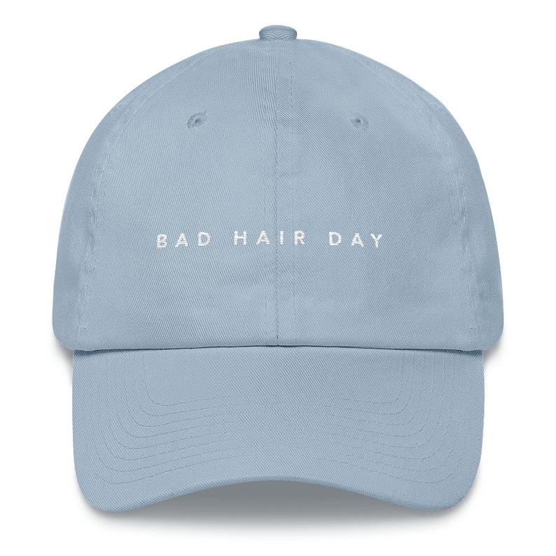 May include: A light blue baseball cap with the text "BAD HAIR DAY" embroidered in white on the front.