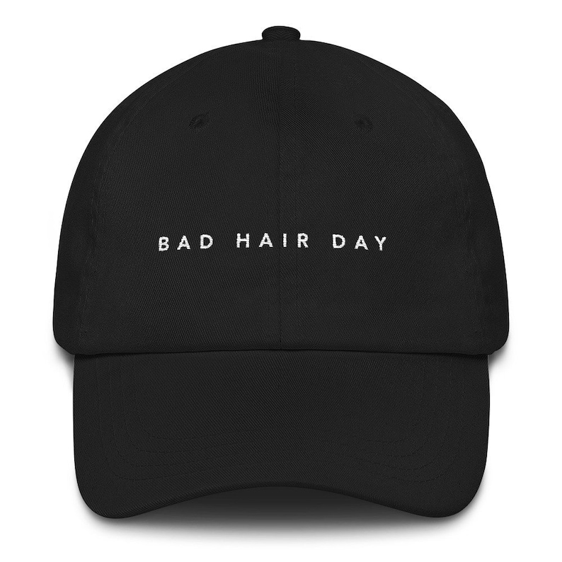 May include: A black baseball cap with white embroidered text that reads "BAD HAIR DAY".