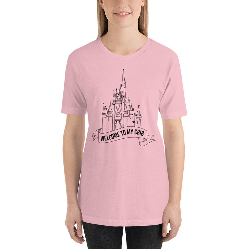 May include: A pink t-shirt with a black outline of Cinderella's castle and the text "Welcome to my crib" on a banner.