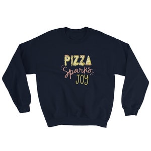 May include: Navy blue sweatshirt with the text "Pizza Sparks Joy" in yellow and pink lettering. The word "Pizza" is made up of pizza slices.
