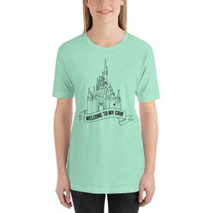 May include: A light green t-shirt with a black outline of Cinderella's castle and the text "Welcome to my crib".