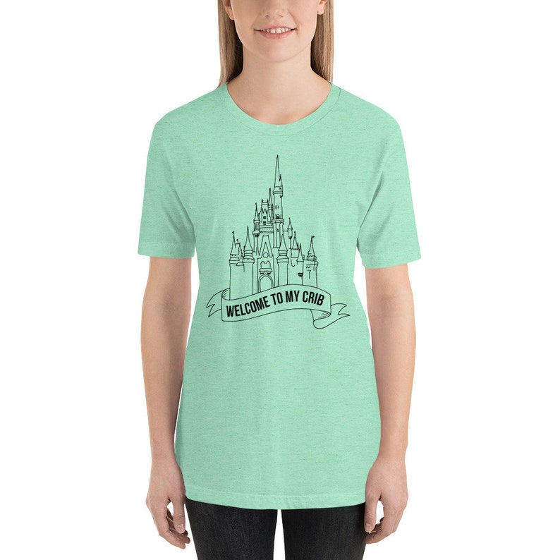 May include: A light green t-shirt with a black outline of Cinderella's castle and the text "Welcome to my crib".