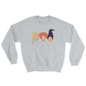 May include: A gray sweatshirt with a graphic of three women's faces. The women have different hair colors and styles. The graphic is in a simple, minimalist style.